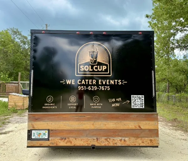 The back of the Sol Cup trailer with the gold arch logo and the words we cater events