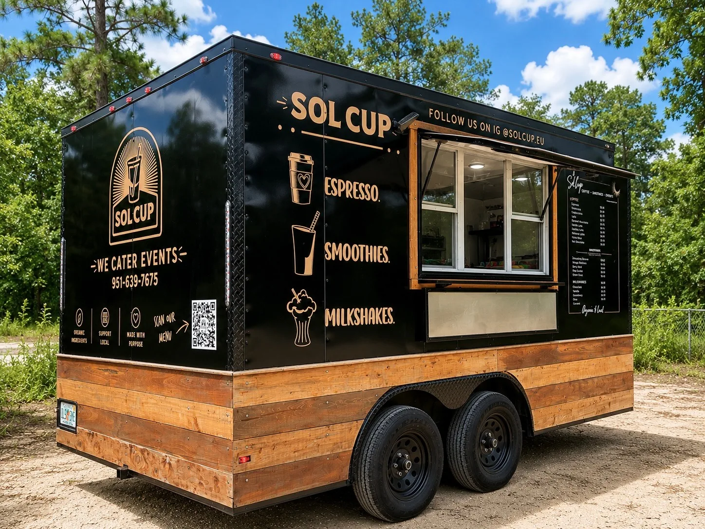 The black Sol Cup trailer with its cedar-plank skirt and gold line-art lettering, parked under pine trees